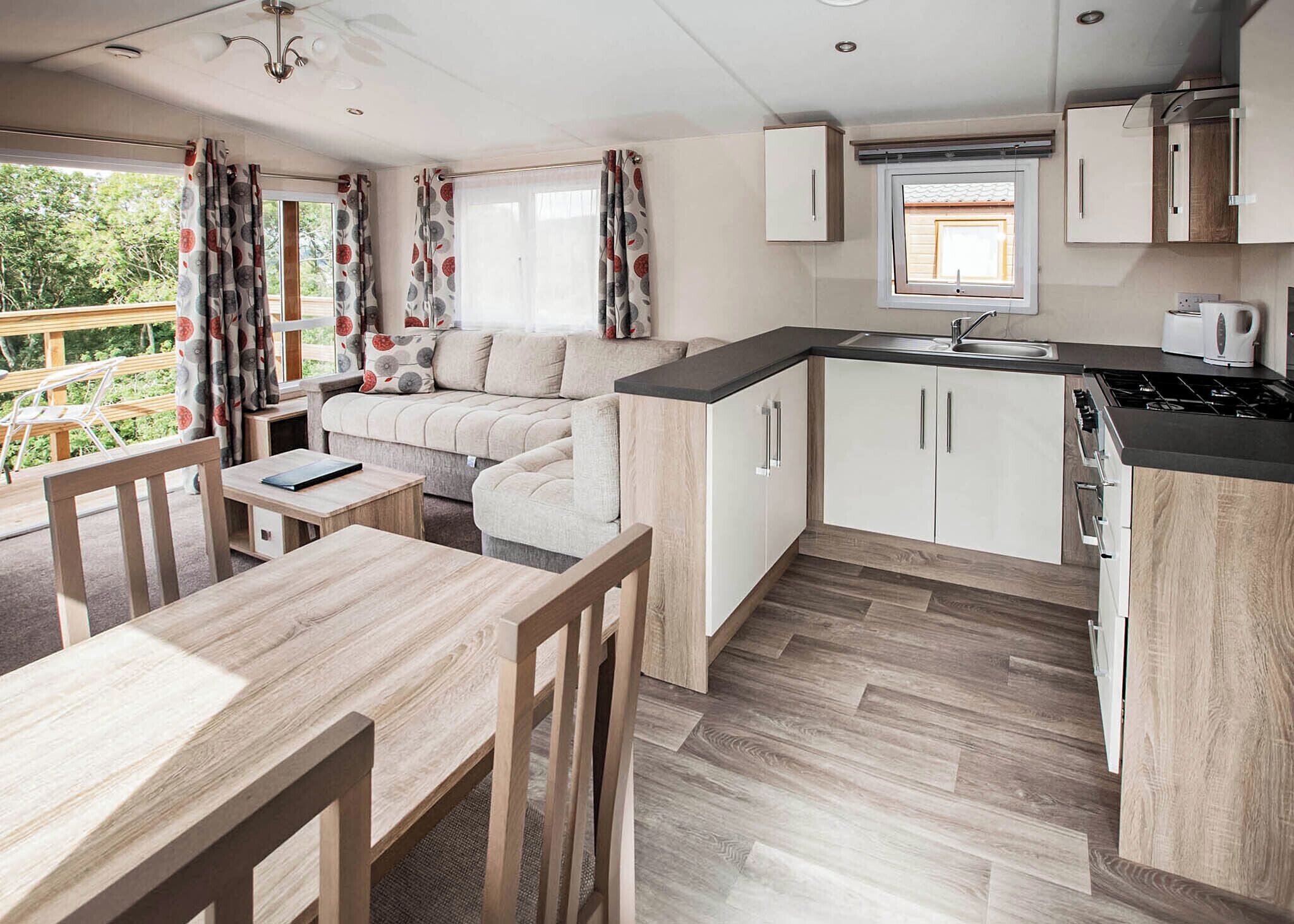 A compact kitchen with a dining area, a sofa, and a window with curtains.