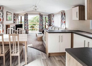 Een moderne keuken met houten kastjes, een eethoek met stoelen en uitzicht op de omgeving.