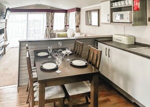 A dining area with a table set for four, a microwave, and a bread box on the counter.