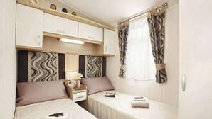 Camera a bordo di un camper, compatta, con due letti, un tavolino e un comodino.