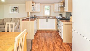 Una cucina funzionale con mobili in legno, un tavolo da pranzo e un divano nella zona giorno.