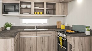 Una cucina moderna con mobili in legno, forno a microonde integrato, lavello e piano cottura.