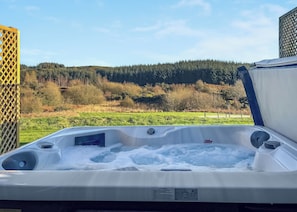 A hot tub with a view of a forested hill. - This Studio Lodge is perfect for couples. (Ringford)
