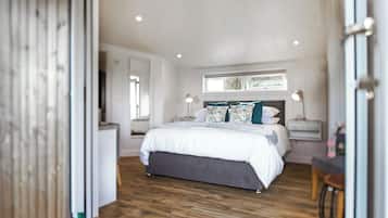 A bedroom with a large bed, bedside tables, a window, and a wooden floor.