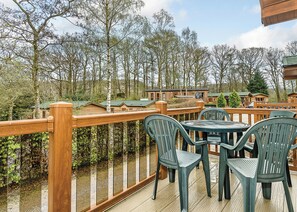 Een houten terras met uitzicht op huisjes en bomen.