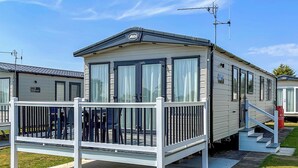 A mobile home with a balcony, a small porch, and a visible door. - Thoughtfully designed for comfort and style. (Withernsea)