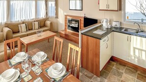 A compact living space with a sofa, dining table set for four, a kitchen area with a sink and stove, and a television. - 3 bedroom accommodation in Newbridge, Nr Yarmouth (Newbridge, Nr Yarmouth)