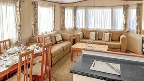 A compact living area with a dining table, chairs, a sofa, and a kitchenette. - 3 bedroom accommodation in Newbridge, Nr Yarmouth (Newbridge, Nr Yarmouth)