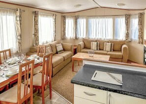 Un espacio habitable compacto con una mesa de comedor, sillas, sofá y kitchenette.
