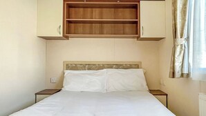 Ein Bett mit weißer Bettwäsche, einem Holz-Kopfteil und einem eingebauten Regal darüber.