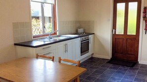 A kitchen with a dining table, chairs, a window, a door, and a tiled floor. - 2 bedroom accommodation in Wroxham, Norfolk Broads (Wroxham, Norfolk Broads)