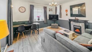 Una sala de estar moderna con un sofá, un televisor, una chimenea y un comedor con sillas y una mesa.