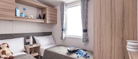 Un dormitorio con dos camas, una ventana con cortinas, una estantería con objetos personales y un armario de madera.