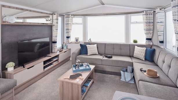 Una sala de estar moderna con una televisión de pantalla plana, un sofá, una mesa de centro y una ventana con cortinas.