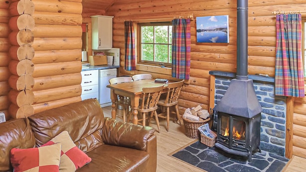A log cabin interior with a fireplace, wooden furniture, a dining area, and a kitchen. - 2 bedroom accommodation in Craobh Haven, Argyll (Craobh Haven, Argyll)