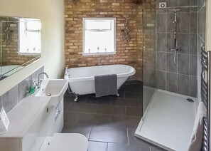 Un baño moderno con una bañera independiente, ducha a ras de suelo y un espejo grande.