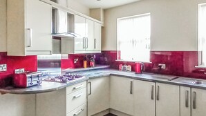 Una cocina moderna con gabinetes blancos, estufa a gas y ventana que proporciona luz natural.