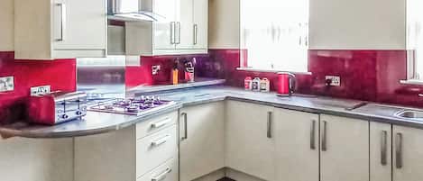 Una cocina moderna con gabinetes blancos, estufa a gas y ventana que proporciona luz natural.