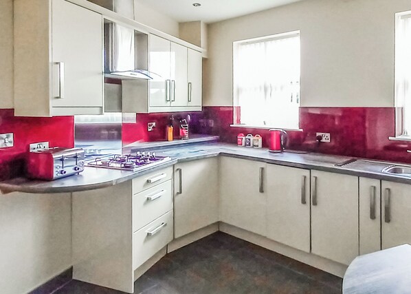 A modern kitchen with white cabinets, a gas stove, and a window providing natural light.
