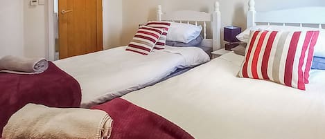 A hotel room with two beds, each with a white headboard, red and white striped pillows, and a red blanket.