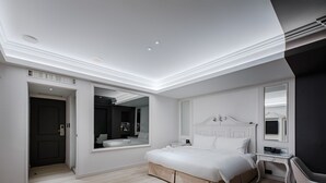 Et moderne hotelværelse med en stor seng, et sengebord, en stol og et spejl.