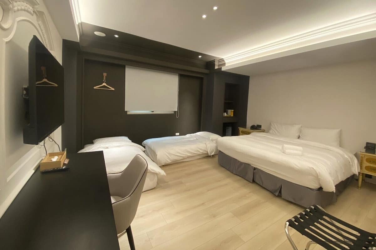 Una habitación de hotel moderna con dos camas, un escritorio, una silla y un televisor.