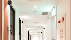 En hotels korridor med døre på begge sider, et tæppe på gulvet og et skilt på den højre væg.