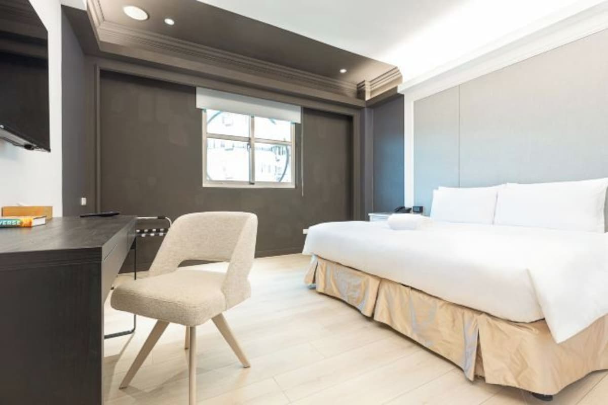 Un dormitorio moderno con una cama grande, un escritorio y una silla.