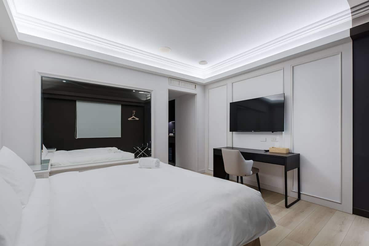 Una habitación de hotel moderna con una cama grande, un escritorio y un televisor.
