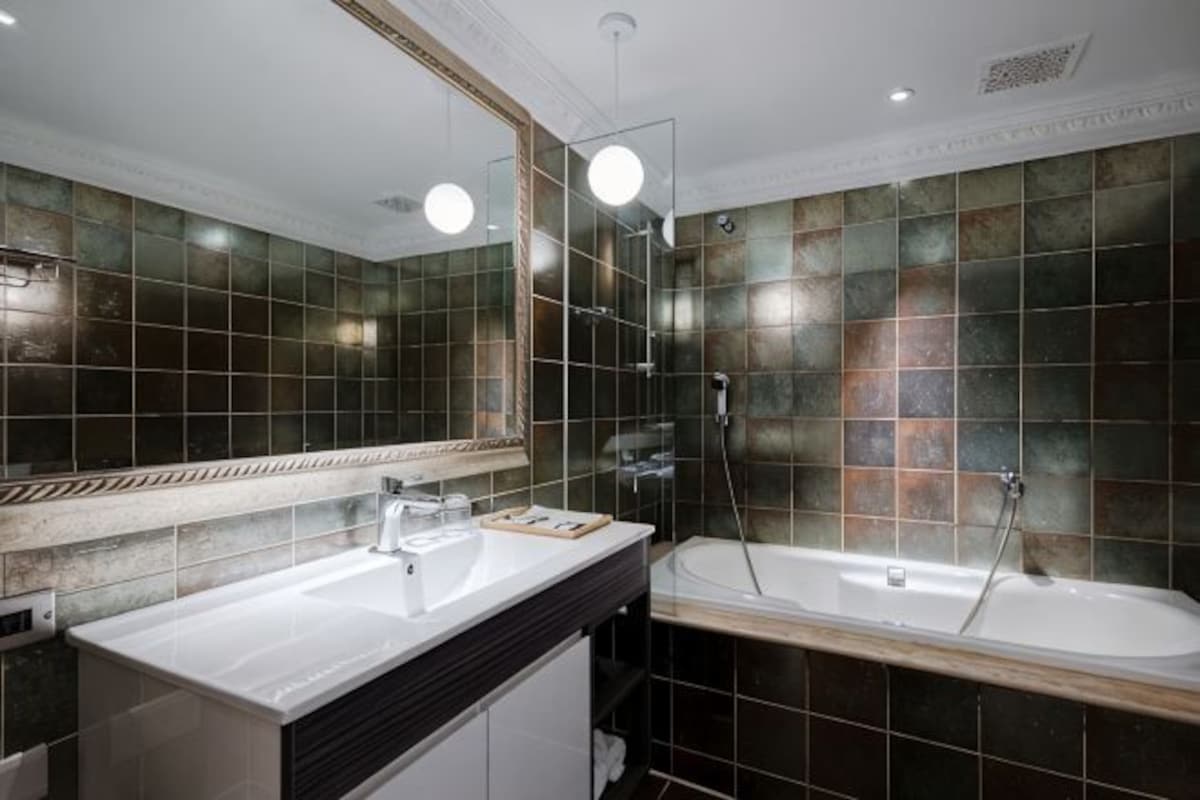Un baño moderno con un espejo grande, dos lavamanos, una bañera y una ducha.