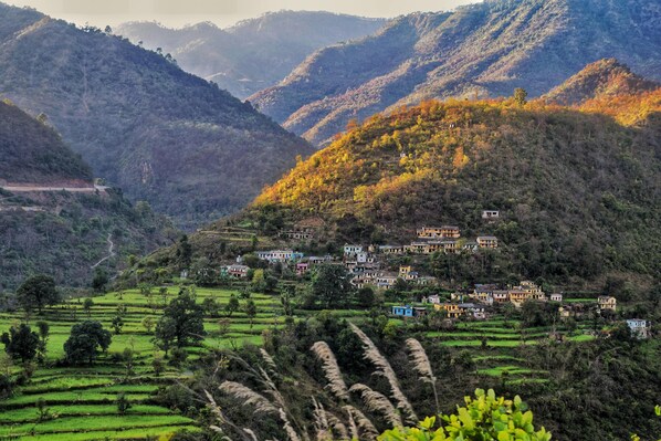 Un pueblo en una ladera con campos en terrazas y casas tradicionales.