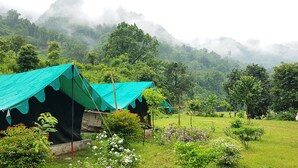 Two tents with green tarps in a lush, green valley with mountains in the background. - The Raajas - Camp & Resorts (Yamkeshwar)