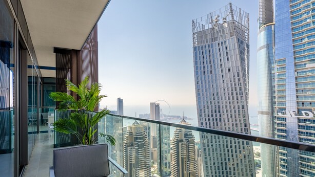 A balcony with a view of high-rise buildings and a Ferris wheel in the distance. - Maison Privee - Exclusive Apt w/ Striking Sea & Dubai Marina Vws (Dubai)