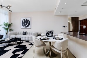 A modern living room with a round dining table, white sofas, and a black and white rug. - Maison Privee - Exclusive Apt w/ Striking Sea & Dubai Marina Vws (Dubai)