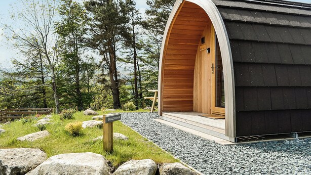 A wooden cabin with an arched entrance, surrounded by trees and a gravel path. - 1 bedroom accommodation in Troutbeck (Troutbeck)