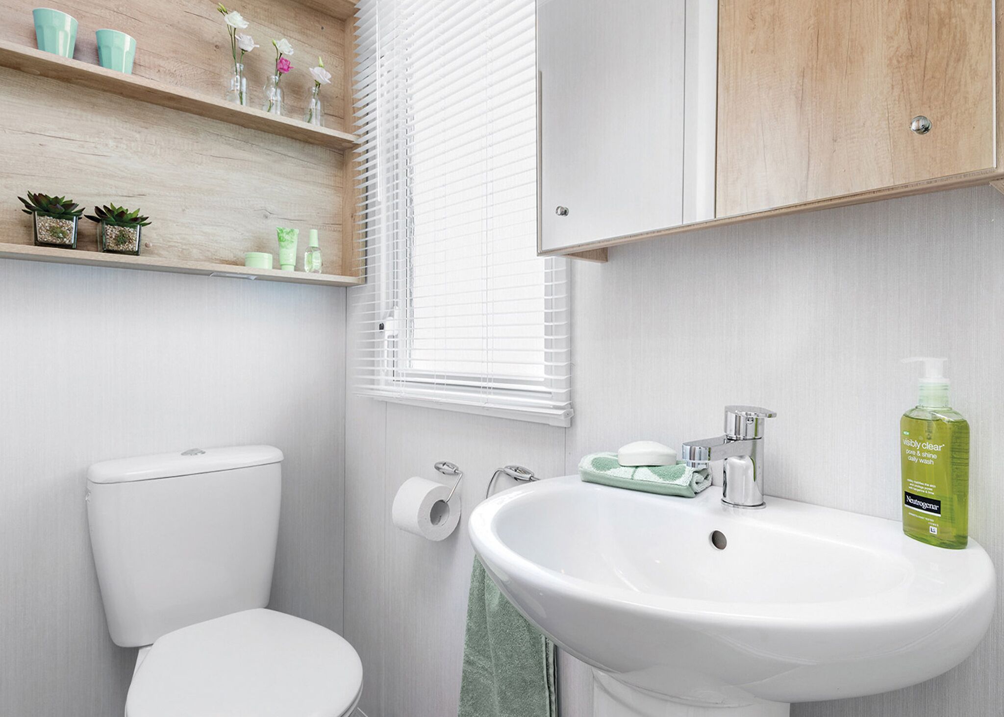 Ein Badezimmer mit Toilette, Waschbecken und Regalen mit Toilettenartikeln.