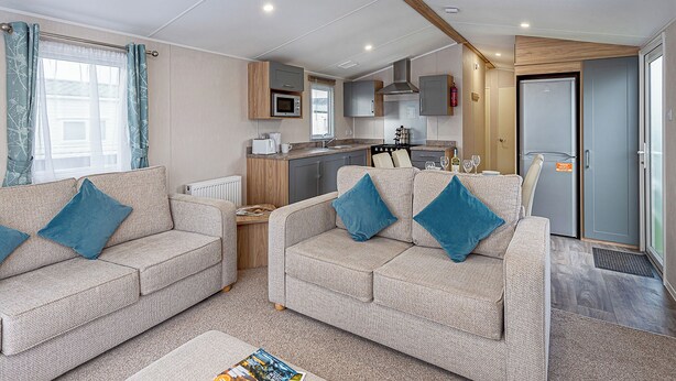 A compact living space with two sofas, a kitchenette, and a door leading to a bathroom.