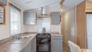 A compact kitchen with a stove, sink, and wooden cabinets.