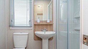A bathroom with a toilet, sink, and glass shower enclosure.