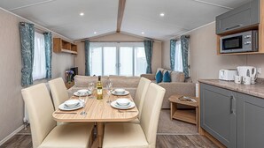 A caravan interior with a dining area, kitchen, and seating space.