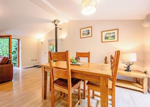A dining area with a wooden table, chairs, and a lamp. There are two framed pictures on the wall. - Decadent lodge designed to exacting, luxury standards. (Cartmel)