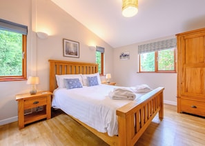 A bedroom with a wooden bed, bedside lamps, a nightstand, a wardrobe, and two windows with curtains. - Decadent lodge designed to exacting, luxury standards. (Cartmel)