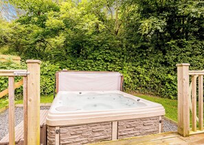 A hot tub in a garden with a wooden deck and stone walls. - Decadent lodge designed to exacting, luxury standards. (Cartmel)