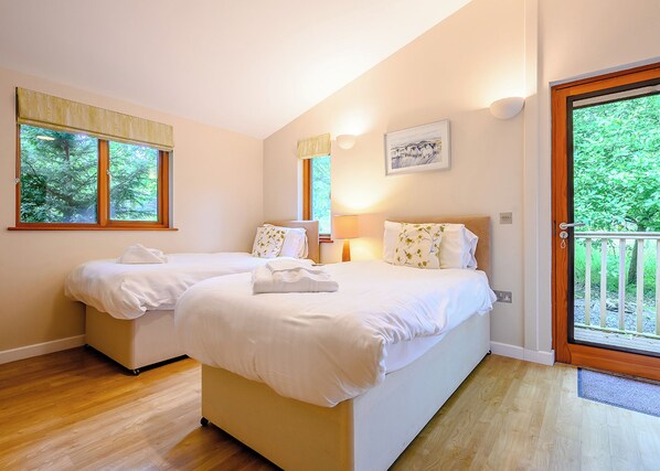 A room with two beds, a window, a door, and a picture on the wall.