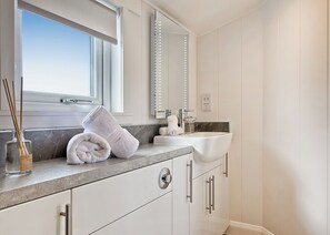A bathroom with a vanity, a mirror, a window, and a towel on the counter.