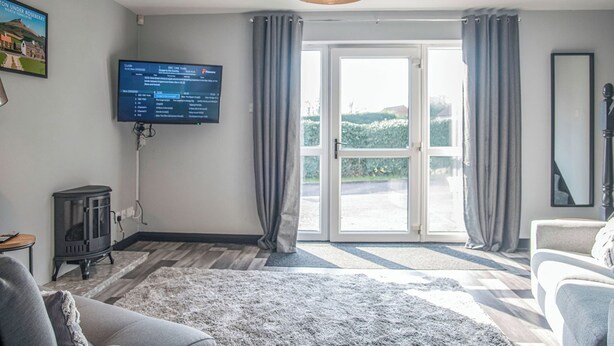 Un salon avec une télévision, une cheminée, un canapé et une grande fenêtre avec des rideaux.