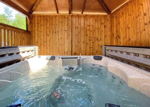Un espace avec un bain à remous, doté de murs en bois et d’une terrasse en bois.
