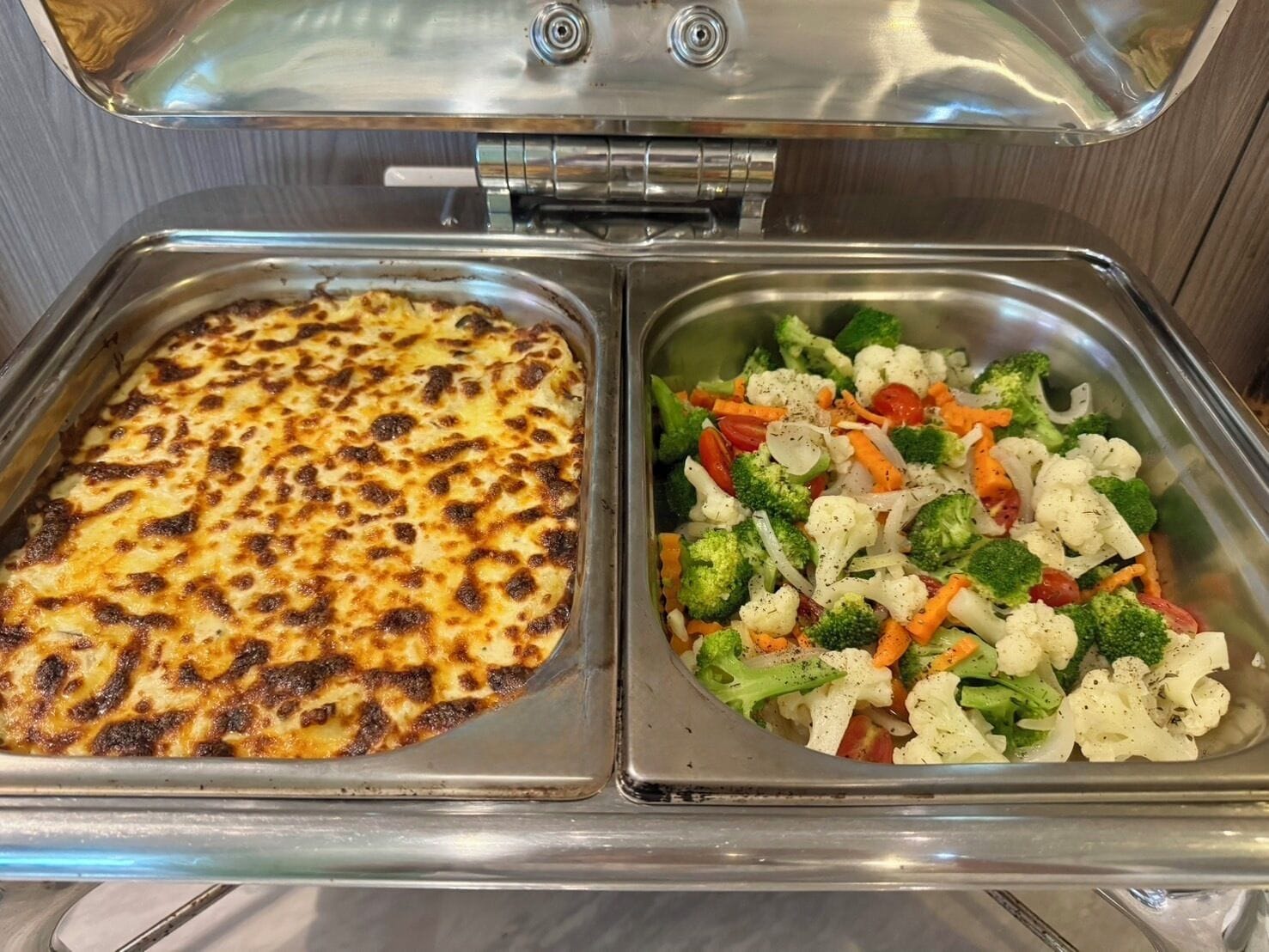 A buffet with a baked dish and a mixed vegetable salad.