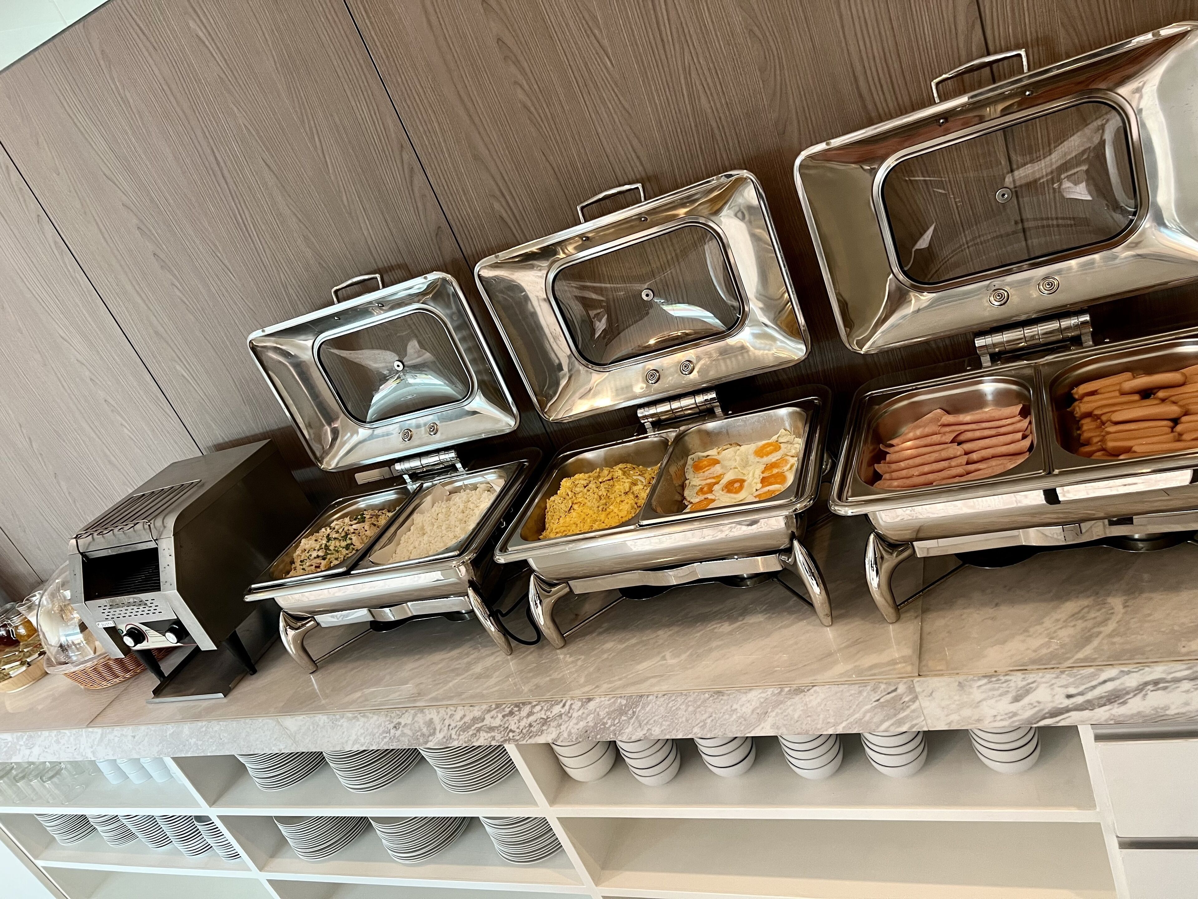A buffet setup with multiple food stations, including rice, eggs, and hot dogs.