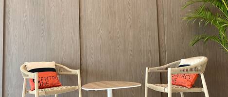 Two wicker chairs with cushions, a small round table, and a wooden wall.
